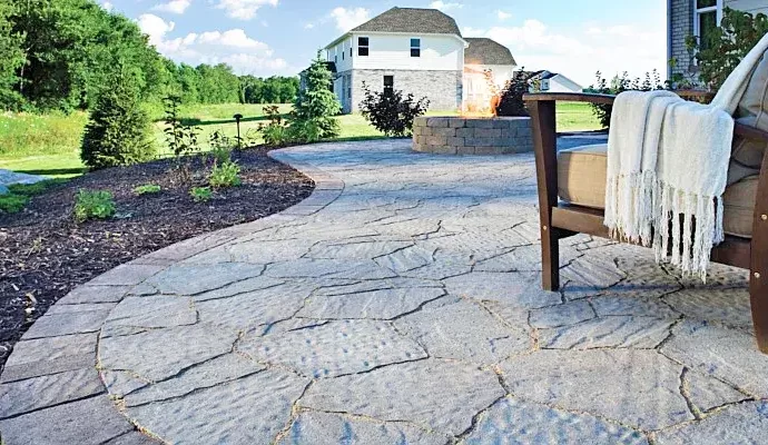 belgard tile design with mulch landscaping, stone firepit in the center