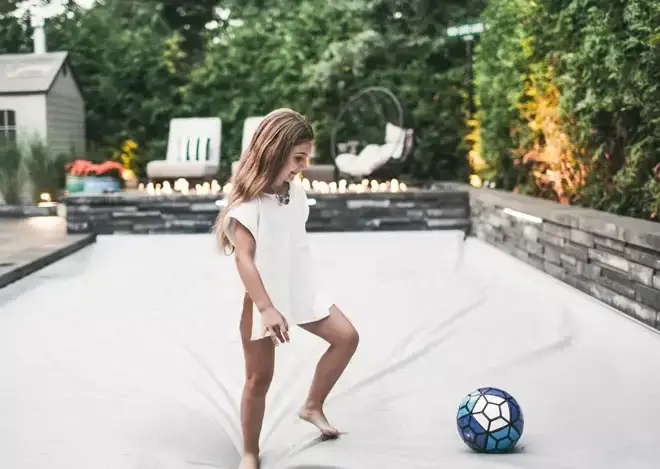 automatic pool cover child playing soccer to show how safe the pool cover is