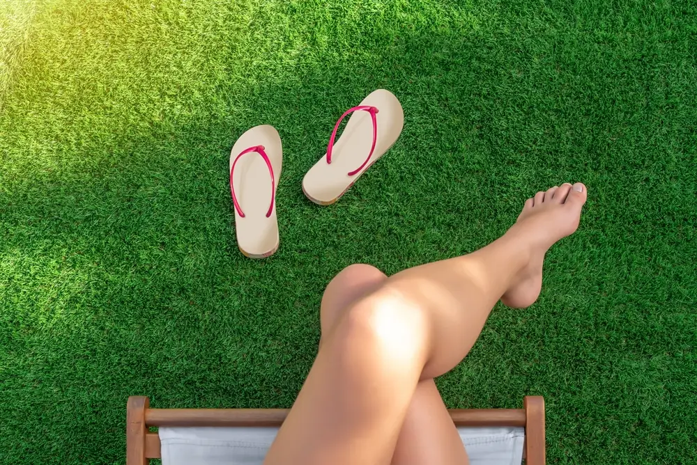 Girl sitting on a hammock chair with bare feet on artificial turf ground
